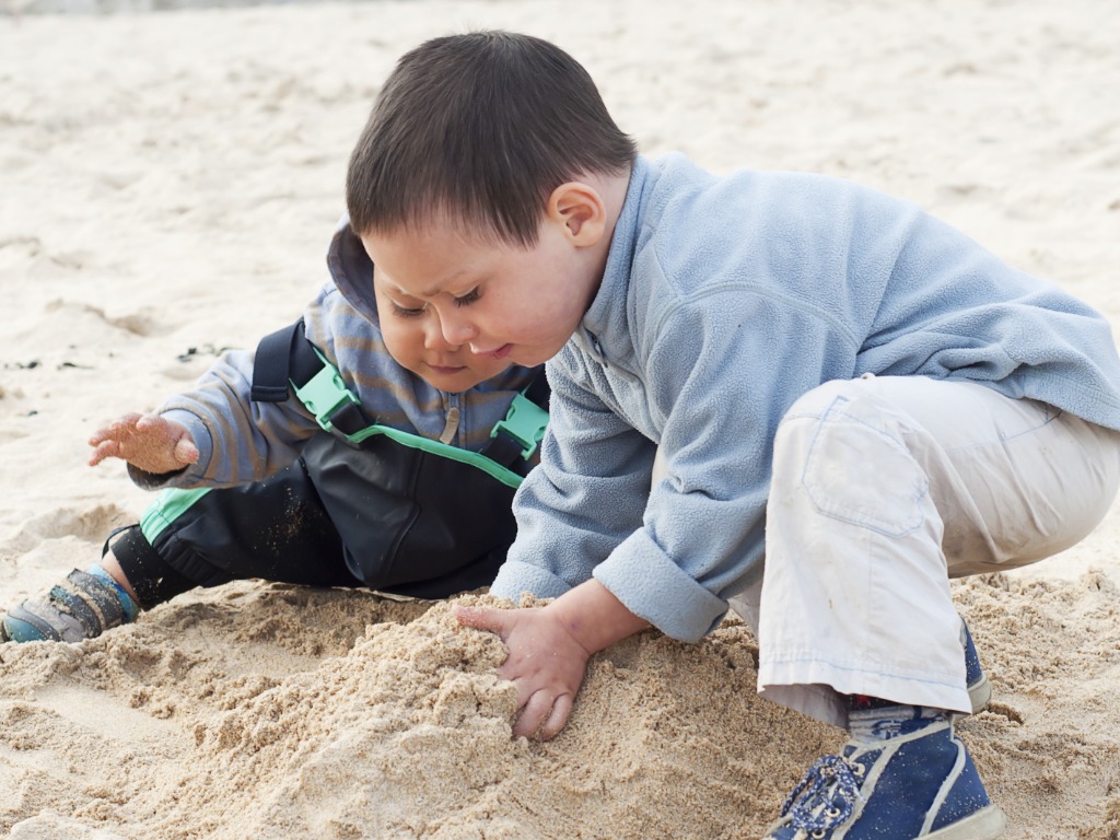 Niños que construyen castillos de arena de la arena en una playa en un día frío.